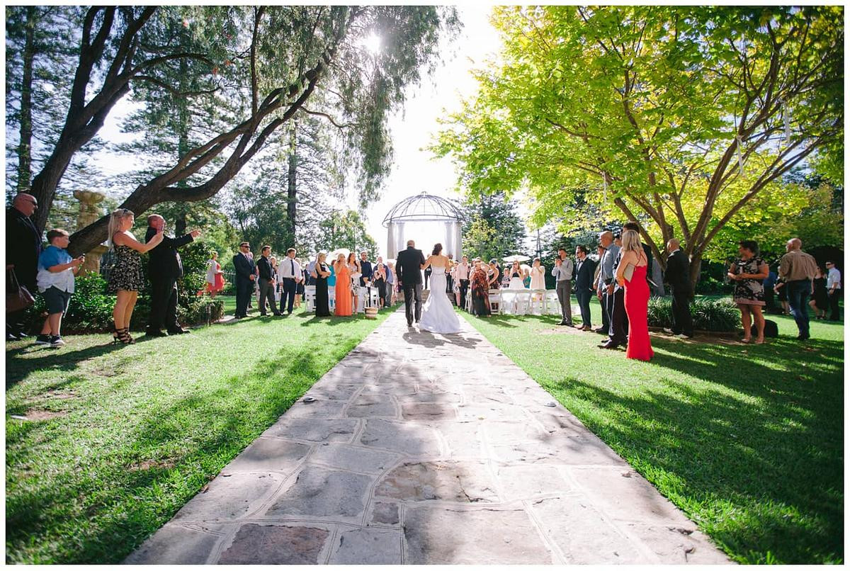 Bride is walking down the aisle during a wedding ceremony at Garden Chateau at Curzon Hall.