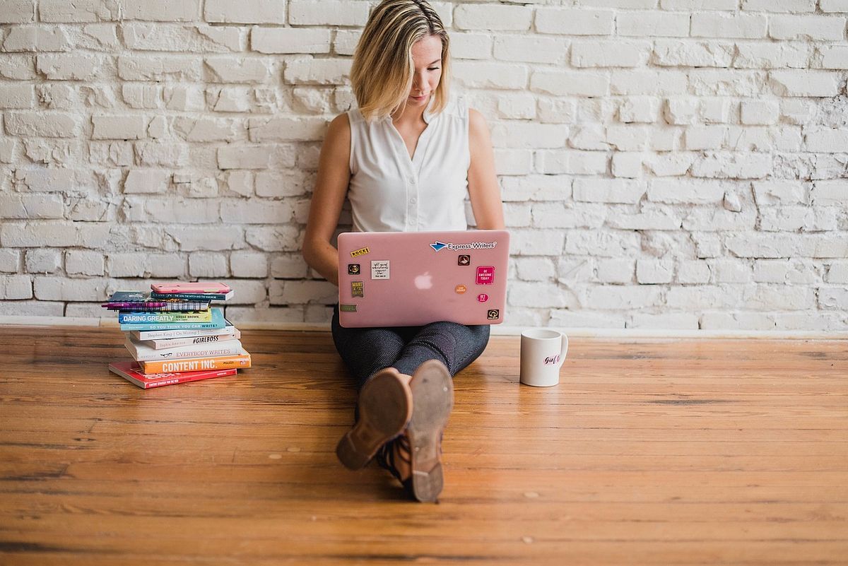 een vrouw met een laptop zittend op de grond en typend